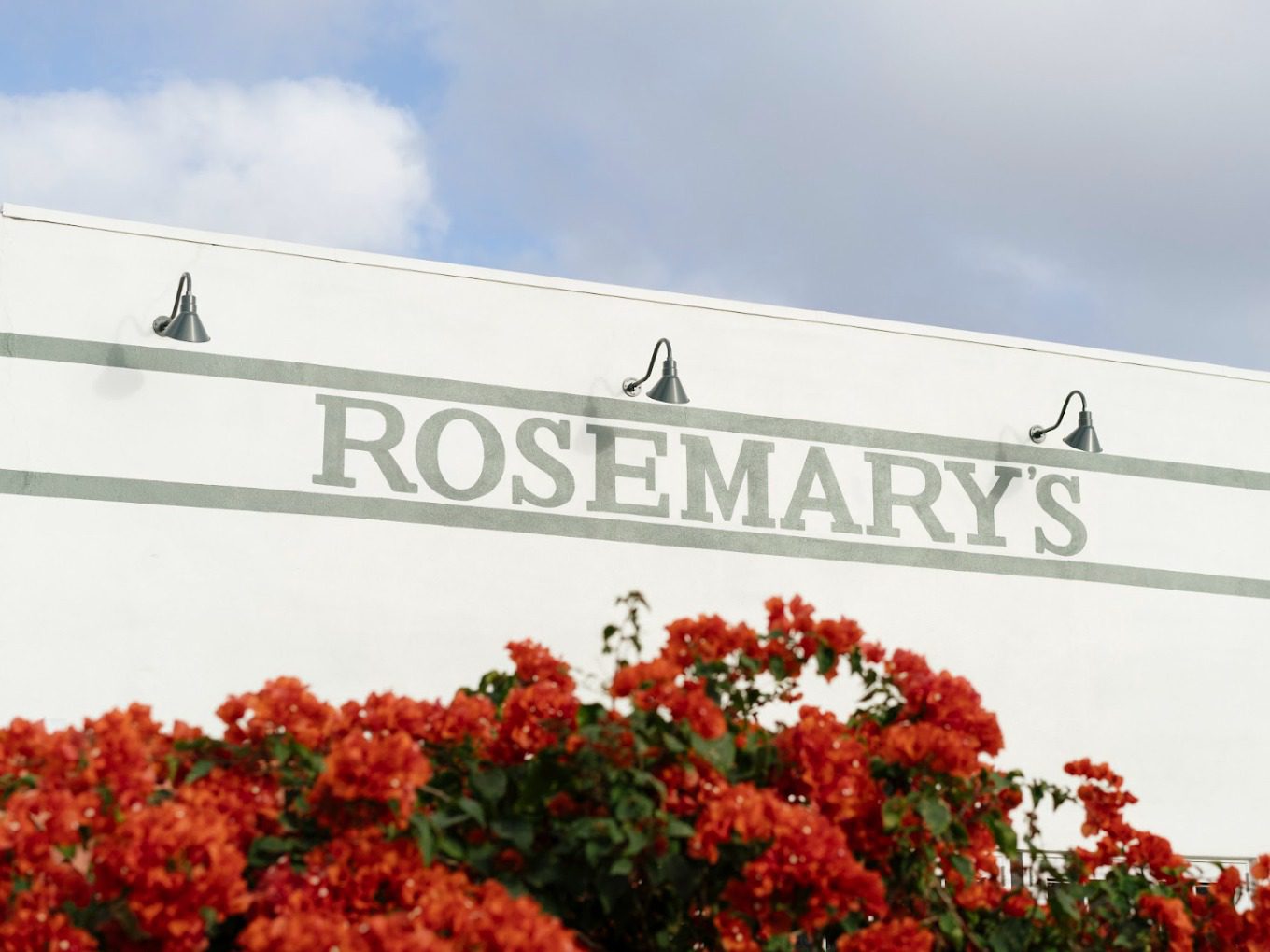 The exterior of Rosemary's Wynwood with its white facade, green lettering and bougainvillea in the Wynwood Arts District, Miami