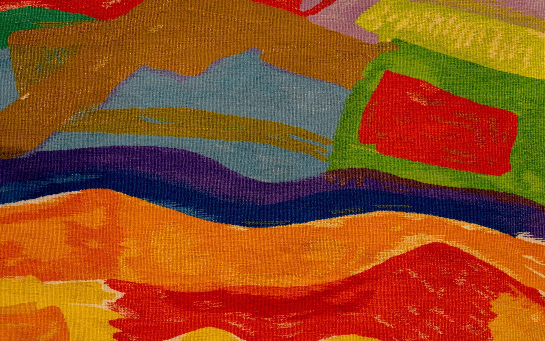 Abstract woven tapestry with vibrant shapes in red, orange, yellow, green, blue, purple and brown