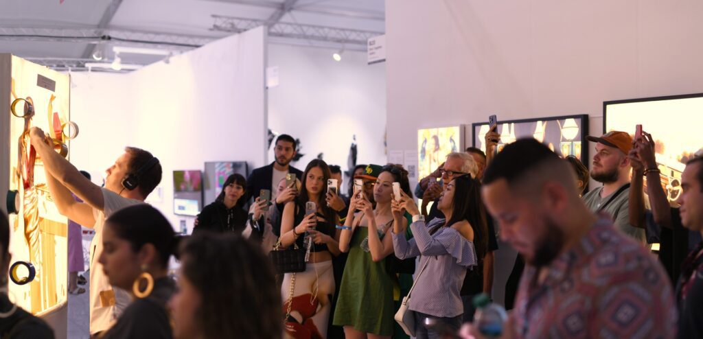 Crowd at a Miami Beach art fair photographing and interacting with contemporary artworks