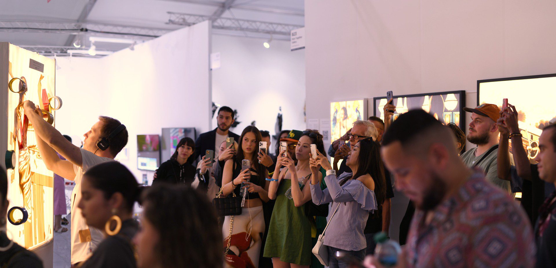 Crowd at a Miami Beach art fair photographing and interacting with contemporary artworks