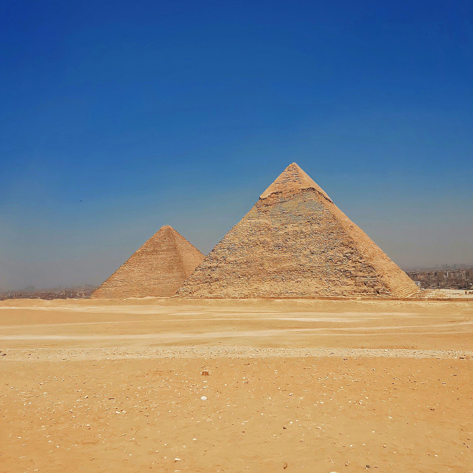 Pyramids of Khafre and Menkaure rising from the Giza Plateau under a blue sky