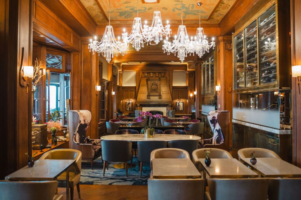 Luxury restaurant dining room with crystal chandeliers, wood paneling and marble tables