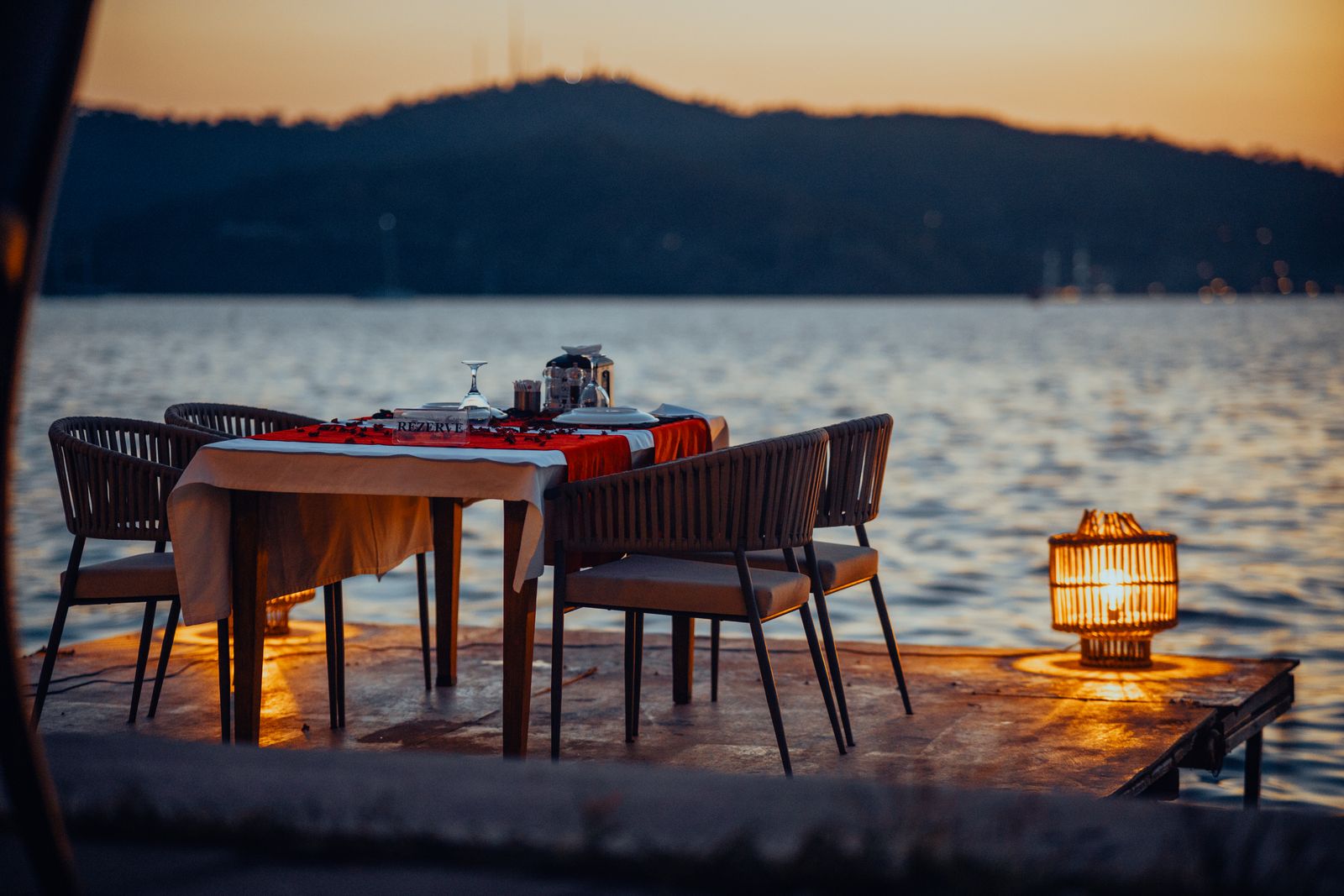 Table set for dinner on a dock beside the water at sunset