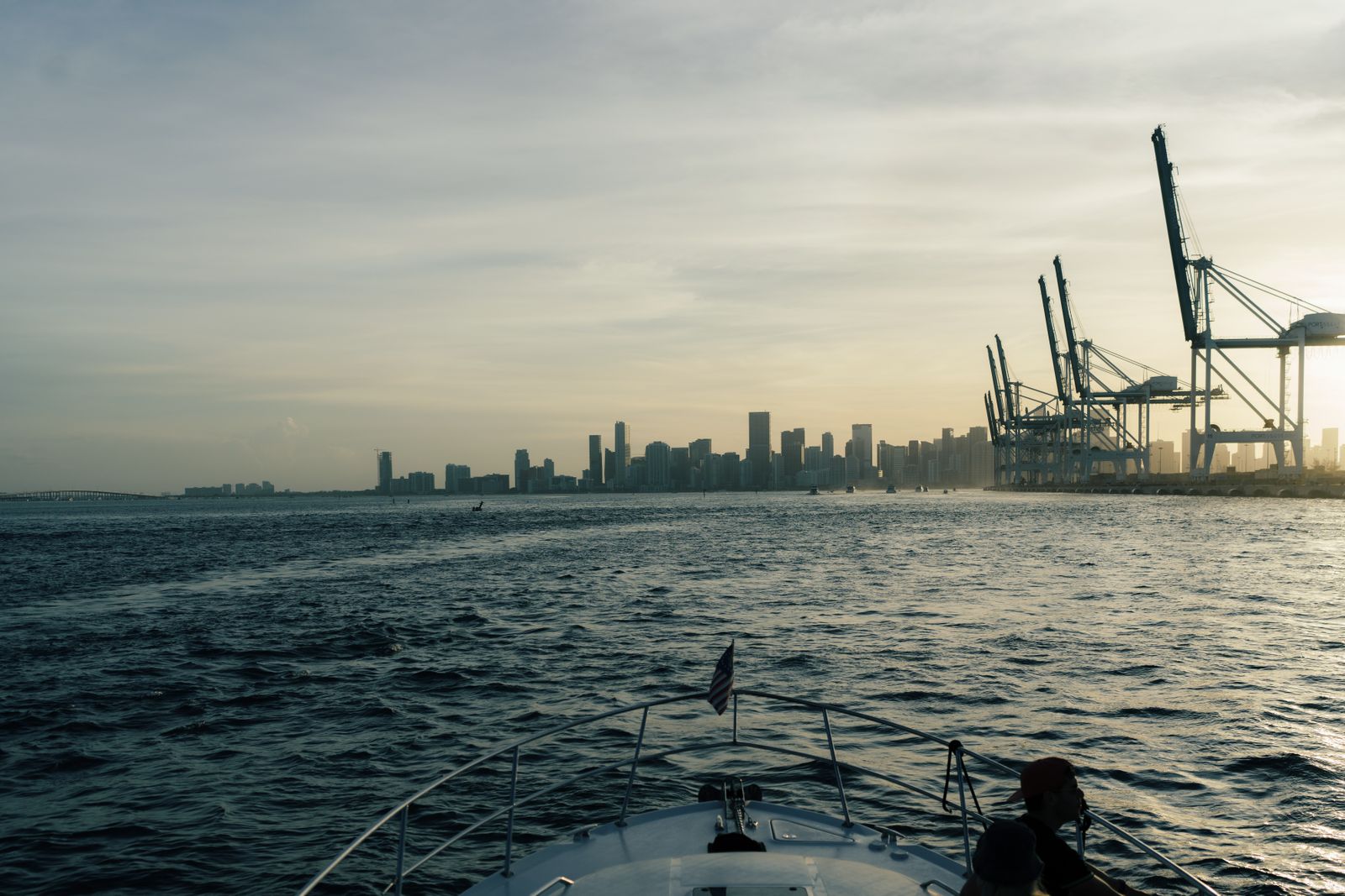 Miami skyline and harbor cranes seen from the deck of a boat at sunset