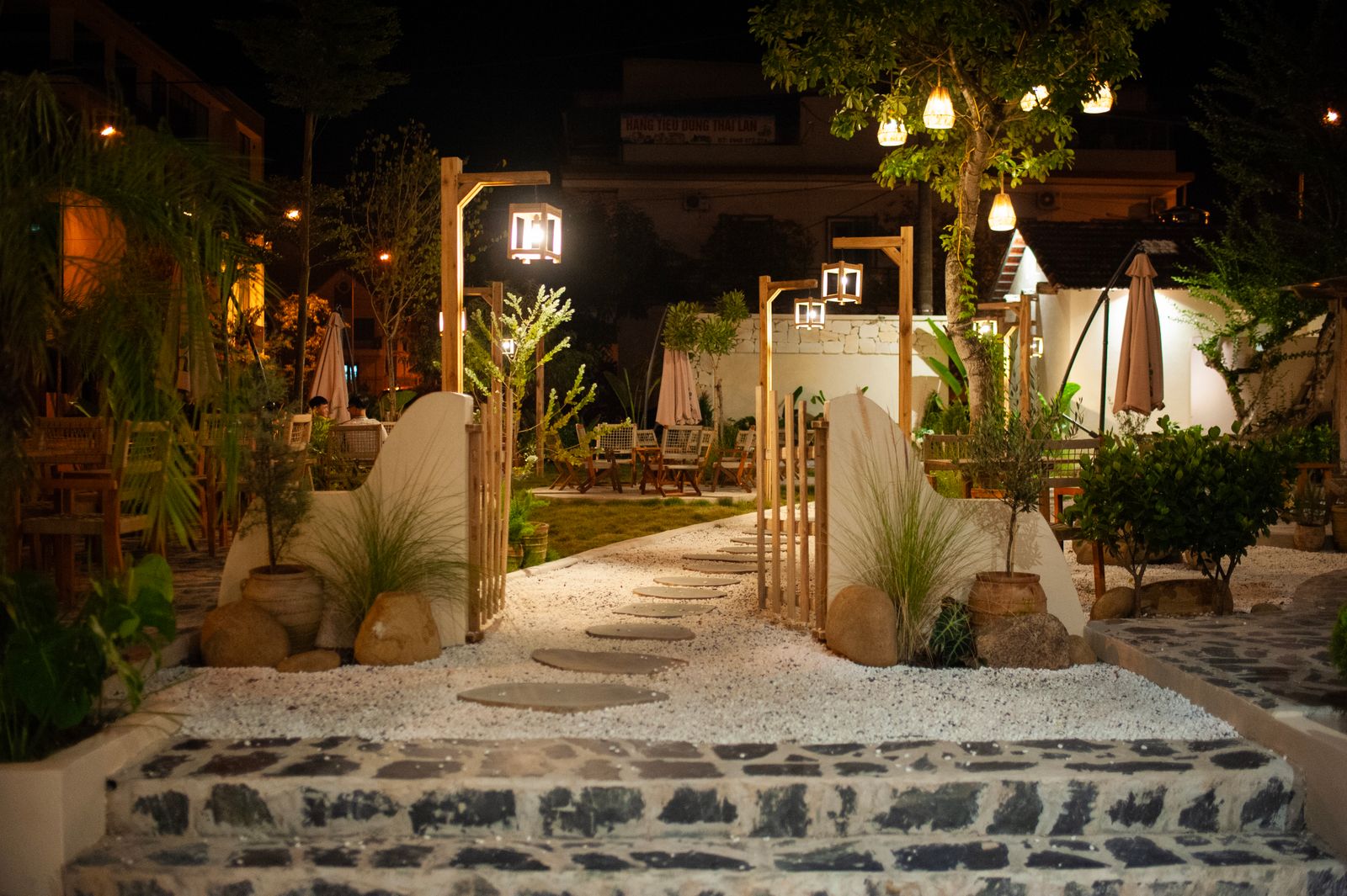 Outdoor garden dining area lit at night and surrounded by greenery