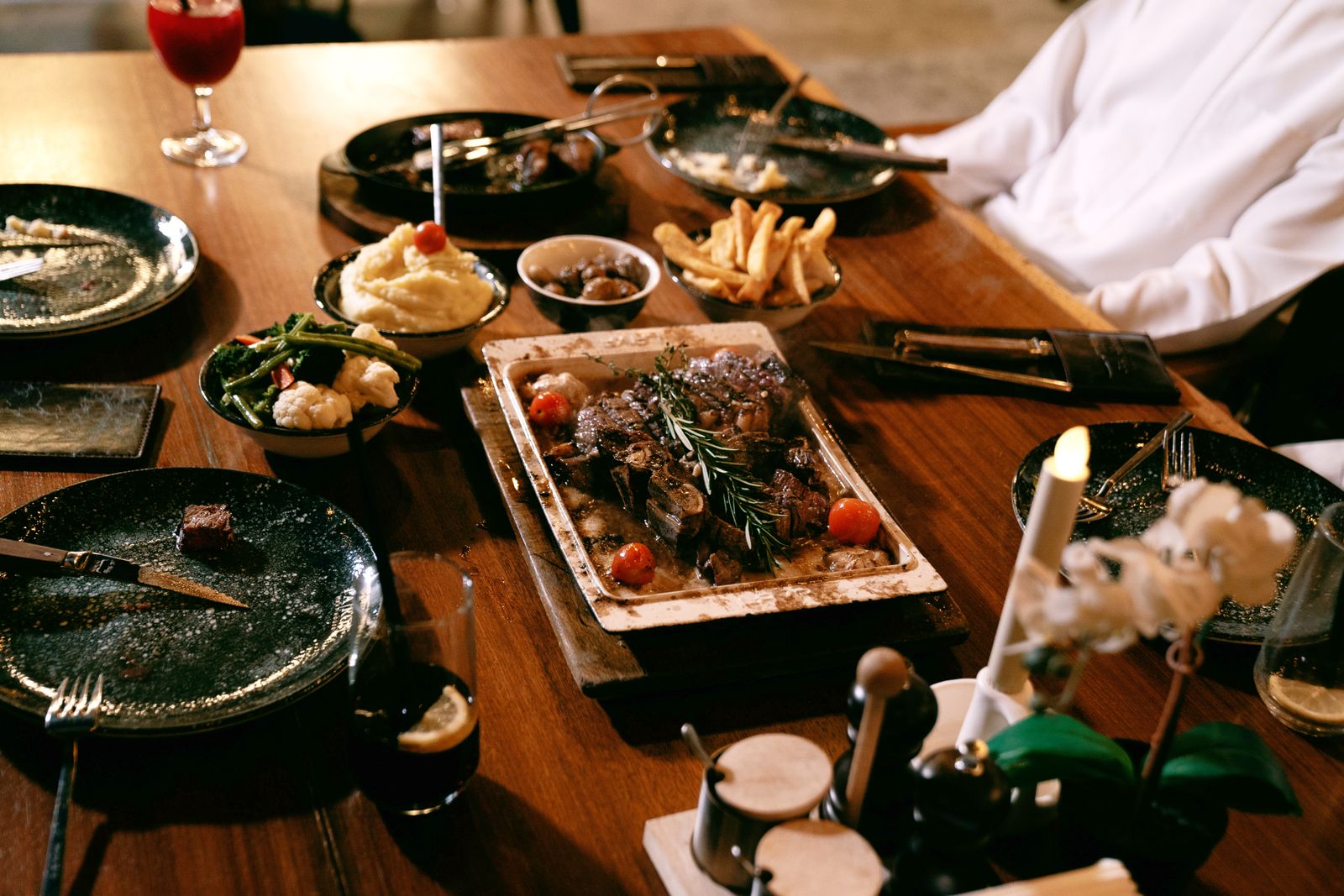 Dinner table with grilled steak, sides and red wine