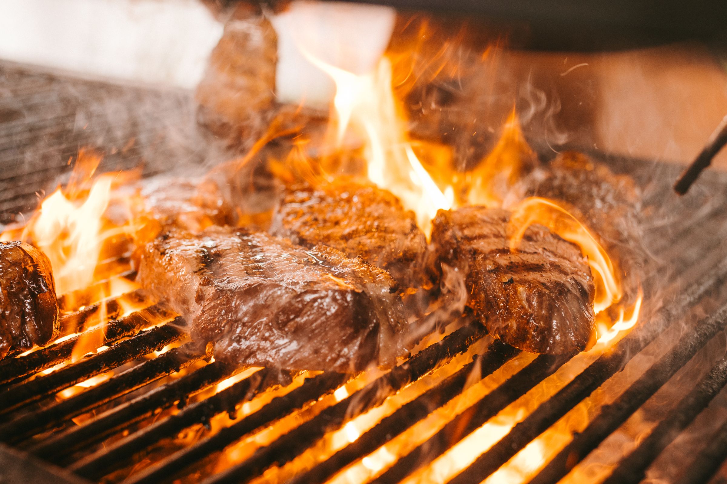 Steaks searing over open flames on a restaurant grill