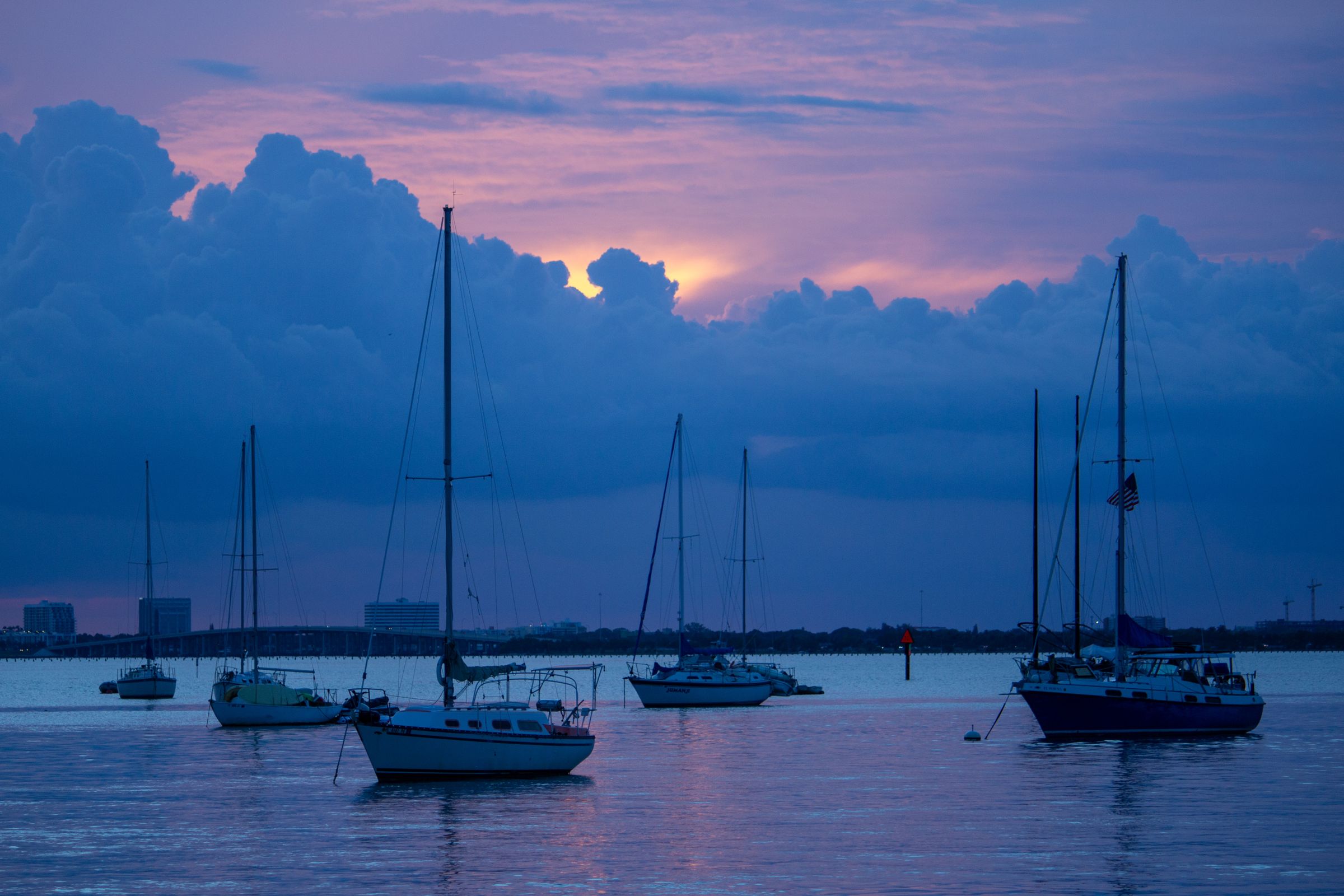 Sailboats at anchor on calm bay water under a pink and violet twilight sky in Miami