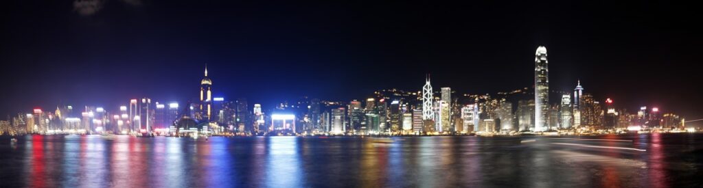 Panoramic nighttime view of Hong Kong Victoria Harbour skyline — global financial hub anchoring the $84 trillion wealth transfer reshaping luxury access for the next generation of UHNWI